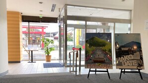 A hotel lobby with a glass entrance, a potted plant, and two framed artworks on easels. - Hotel Promote Hakodate (Hakodate)