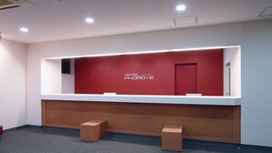 A reception desk with a red wall and a white counter. - Hotel Promote Hakodate (Hakodate)