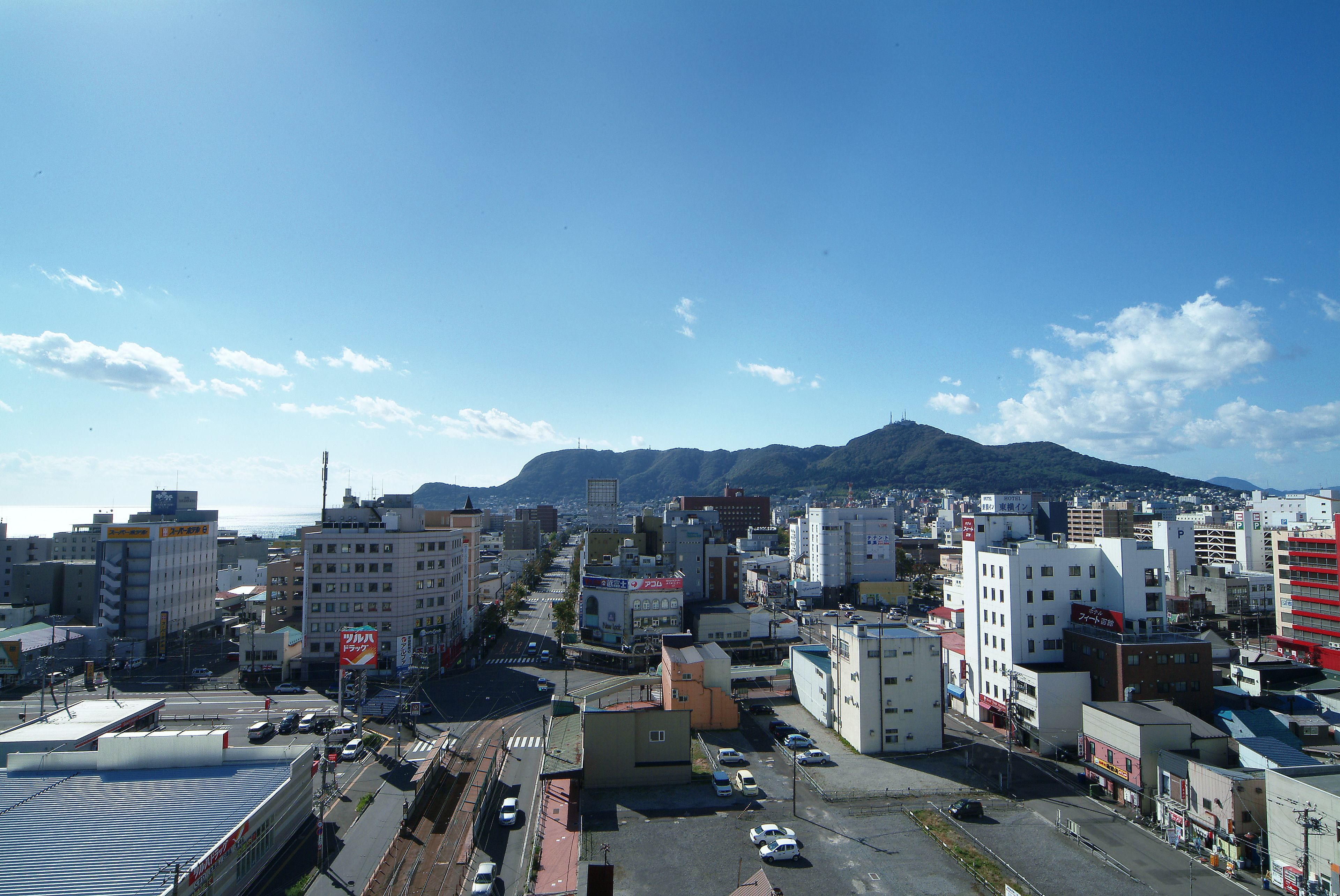 A cityscape with buildings, a road, and a mountain in the background.
