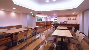 A spacious dining area with multiple tables and chairs, a kitchen in the background, and a modern ceiling design. - Hotel Promote Hakodate (Hakodate)