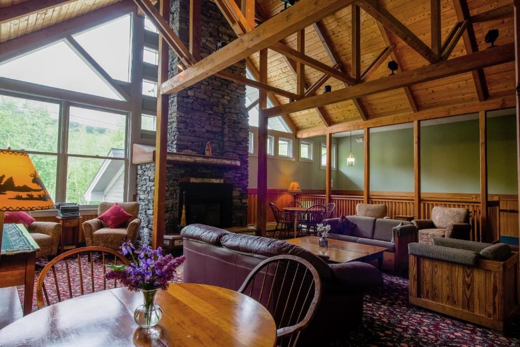 A cozy interior with a stone fireplace, wooden beams, and a seating area with sofas and chairs.