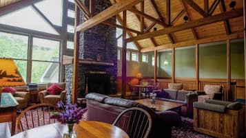 Un interior acogedor con chimenea de piedra, vigas de madera y una zona de estar con sofás y sillones.