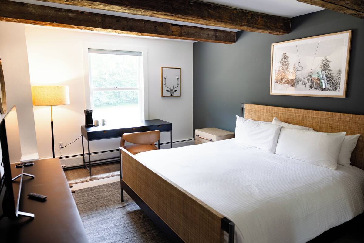 A neatly arranged bedroom with a bed, desk, chair, and a lamp.