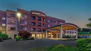 A Courtyard by Marriott hotel with a stone facade, multiple floors, and a covered entrance. - Courtyard Oneonta (Oneonta)