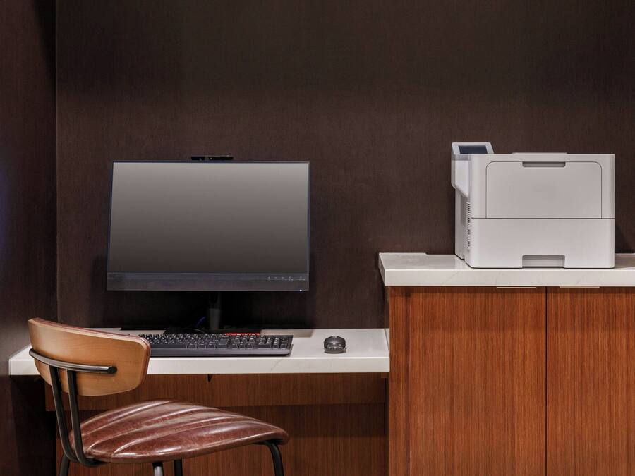 Un espacio de trabajo moderno con un monitor de computadora, teclado e impresora sobre un escritorio.