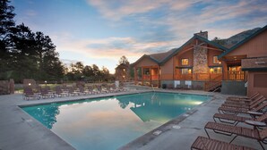 A pool area with lounge chairs and a building with a stone facade. - WorldMark Estes Park (Estes Park)