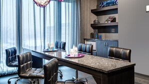 A modern conference room with a large table, black leather chairs, and decorative hanging lights.