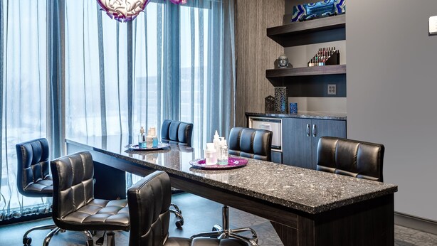 Una sala de conferencias moderna con una mesa grande, sillas de cuero negro e iluminación colgante decorativa.