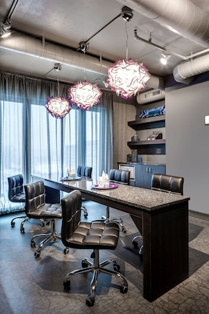 A modern conference room with a large table, black leather chairs, and decorative hanging lights.