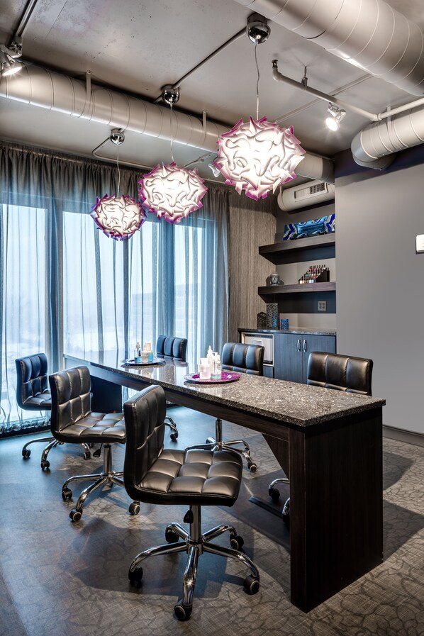 A modern conference room with a large table, black leather chairs, and decorative hanging lights.