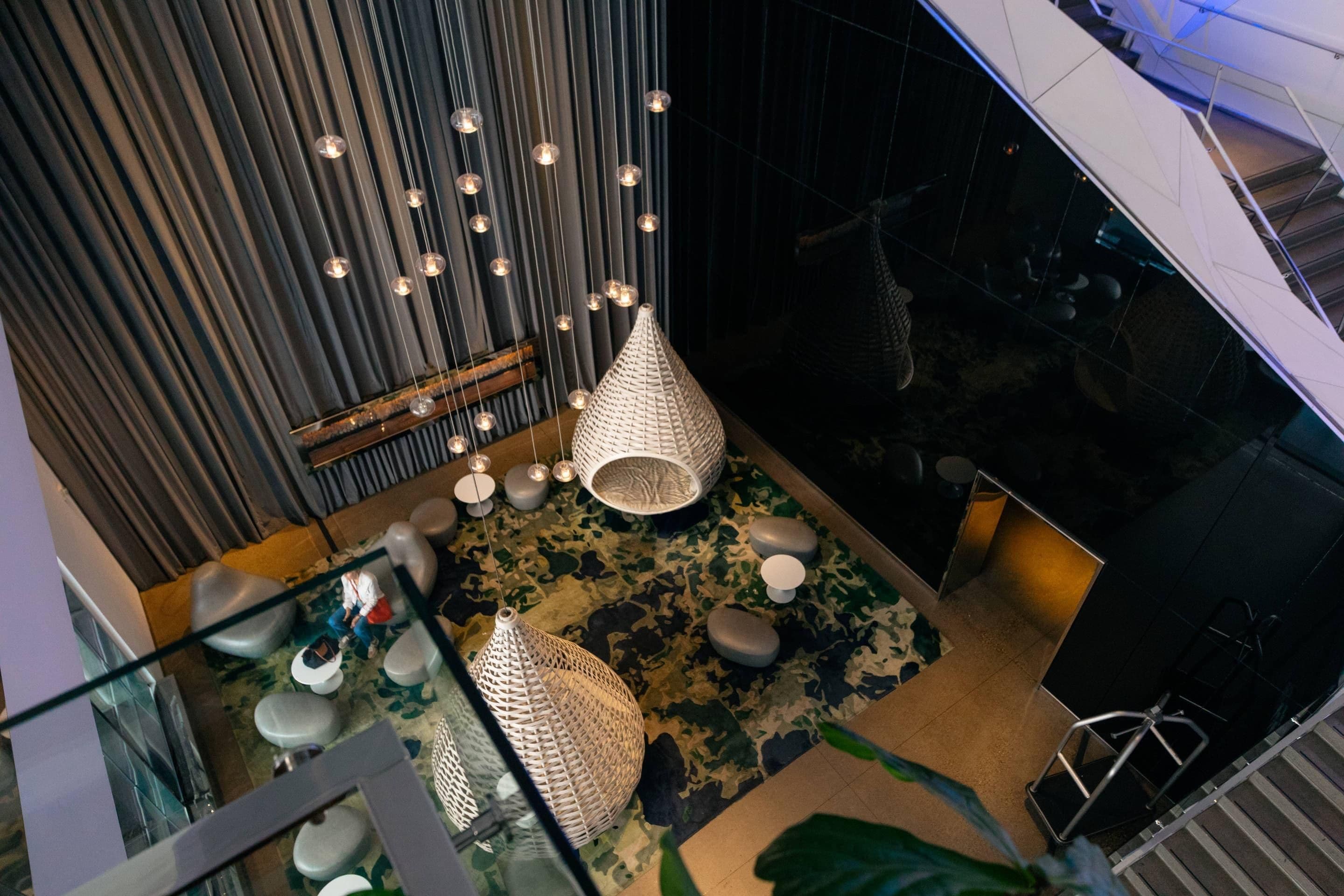 Un interior moderno con luces colgantes, un suelo estampado y una escalera.