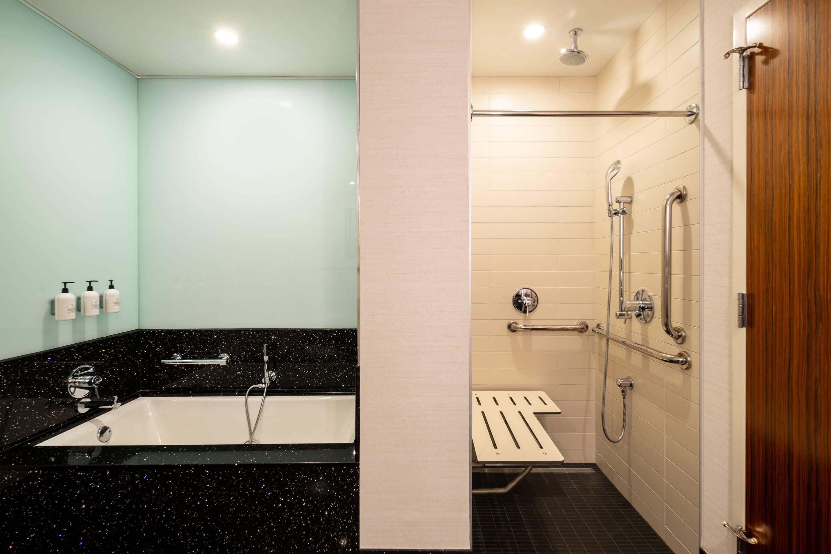 A bathroom with a bathtub, a shower area with grab bars, and a toilet.