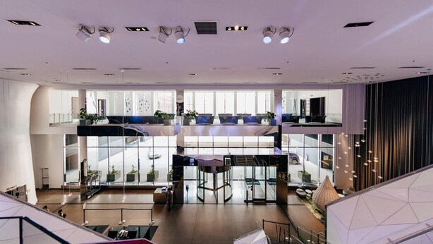 A modern hotel lobby with a spacious atrium, multiple levels, and a central seating area.