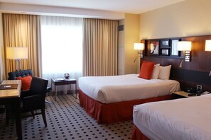 A hotel room with two beds, a desk, a chair, a lamp, and a window with curtains. - Radisson Blu Mall of America (Bloomington)