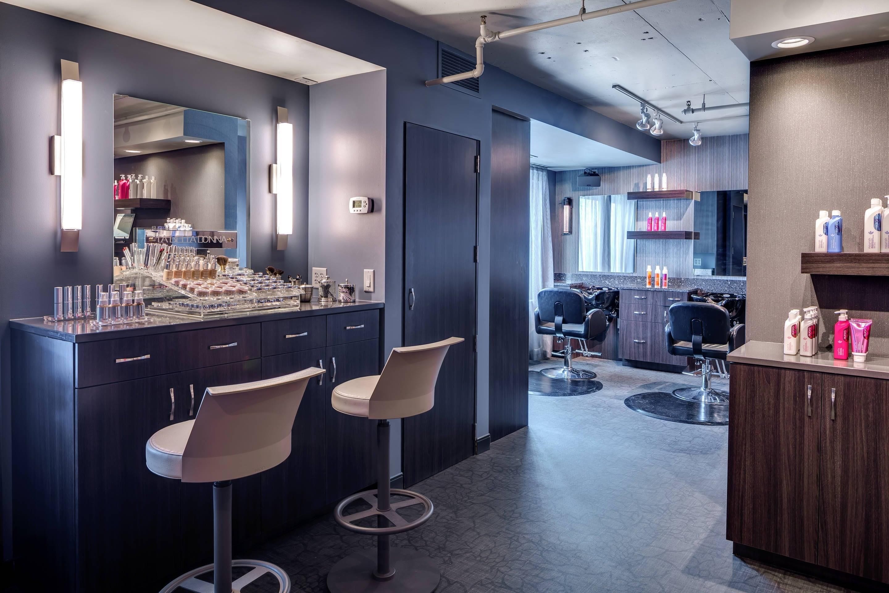 Un área de bar moderna con dos taburetes, una barra con varios artículos y vistas a un salón.