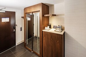 A hotel room with a wooden cabinet, a coffee machine, and a door with a calendar. - Radisson Blu Mall of America (Bloomington)