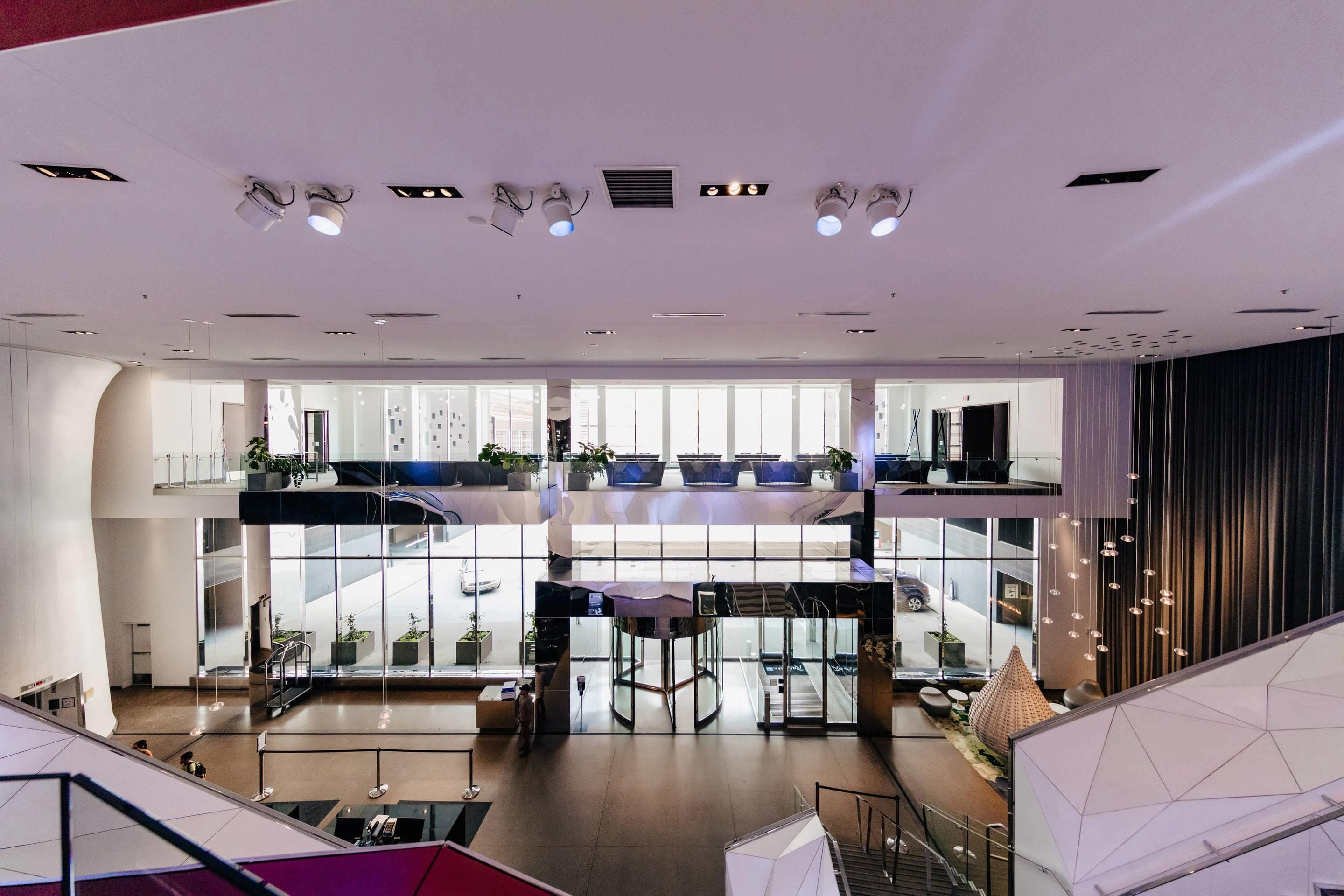 A modern hotel lobby with a spacious atrium, multiple levels, and a central seating area.