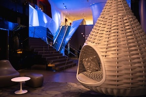 A modern interior with a unique hanging chair, a staircase, and a small round table. - Radisson Blu Mall of America (Bloomington)