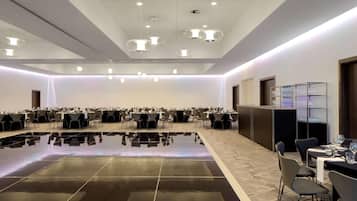 A conference room with a polished floor, tables, chairs, and a bar area with glassware.