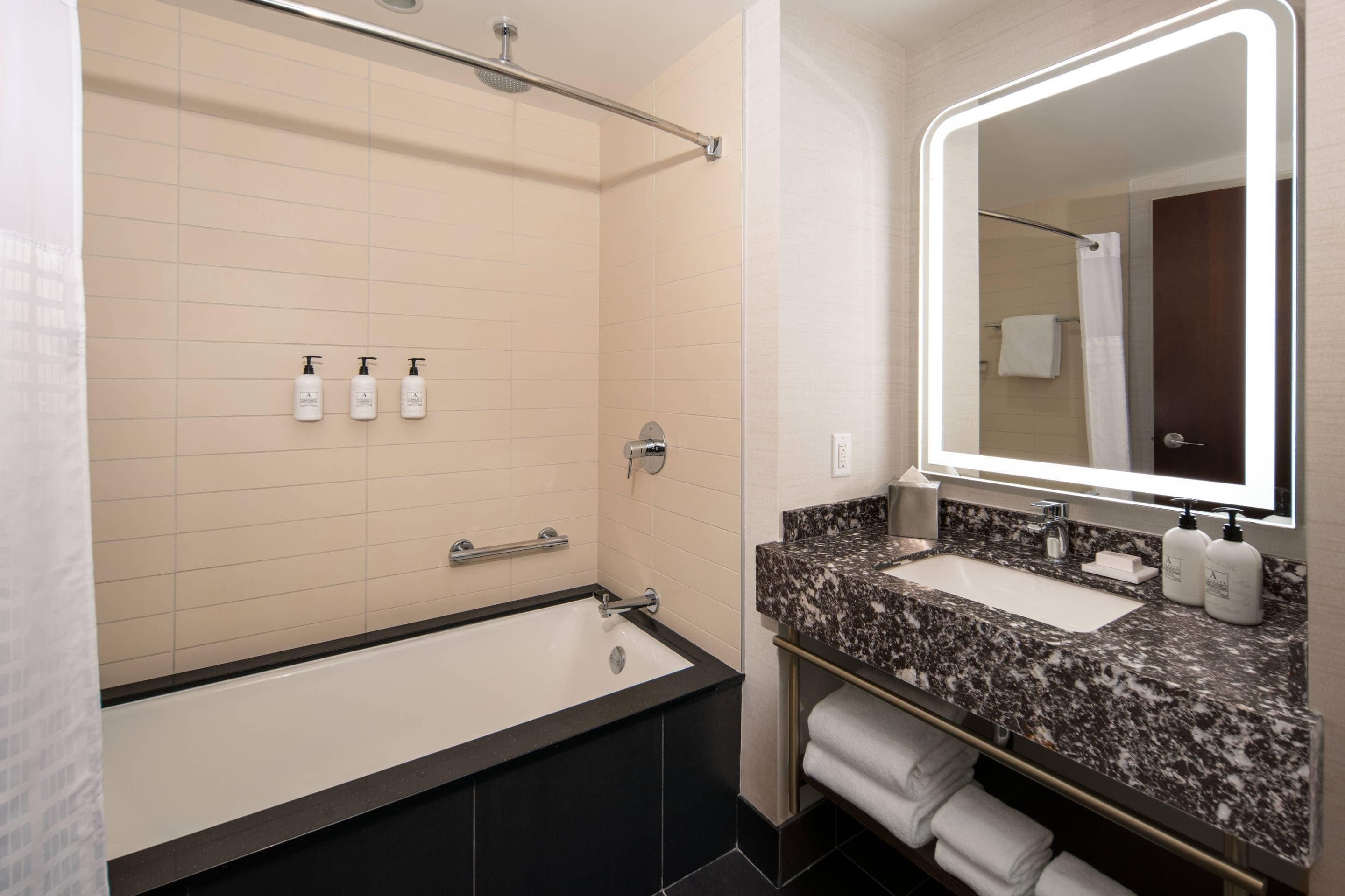 Un baño moderno con bañera, lavamanos y un espejo grande.