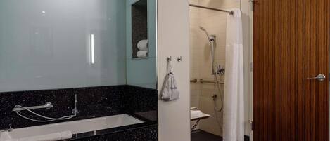 A modern bathroom with a black speckled countertop, a shower area, and a wooden door.