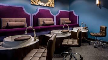 A room with three sinks, two chairs, and a vanity area with a mirror.