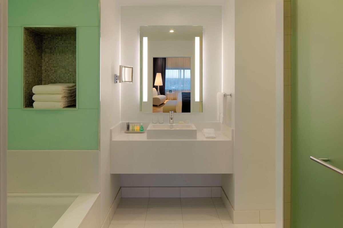 A modern bathroom with a large mirror, a sink, and a towel rack.