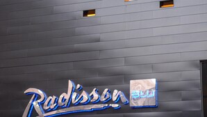 A building facade with a modern design, featuring a series of evenly spaced rectangular windows and a prominent illuminated sign with the name "Radisson Blu".