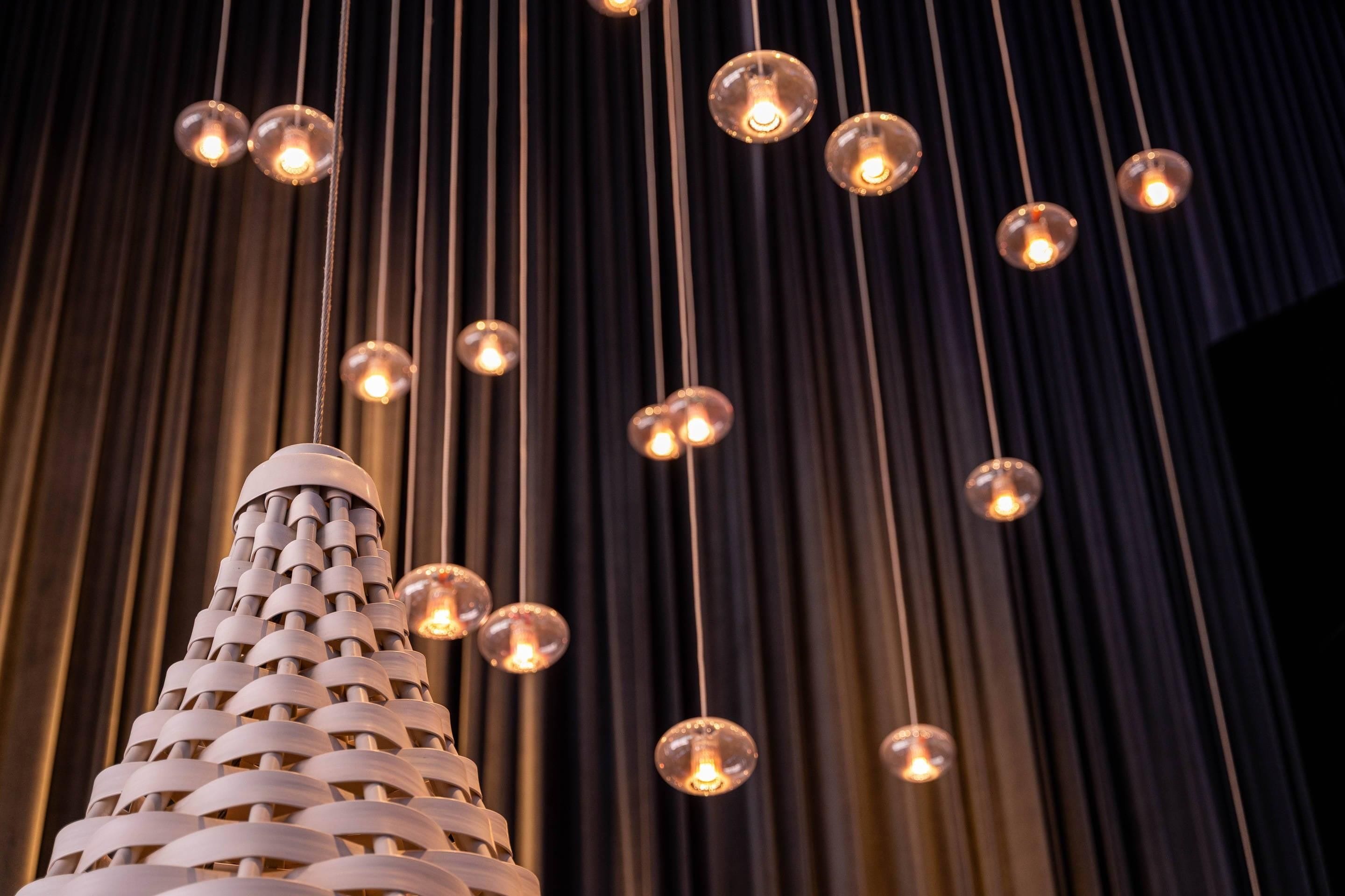 A modern chandelier with multiple spherical bulbs and a unique woven structure.