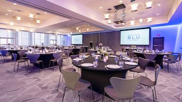 A conference room with round tables, chairs, and a large screen displaying 'RADISSON BLU MALL OF AMERICA'.