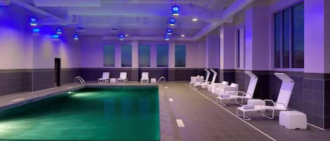 A swimming pool with lounge chairs and a ceiling with blue lights.