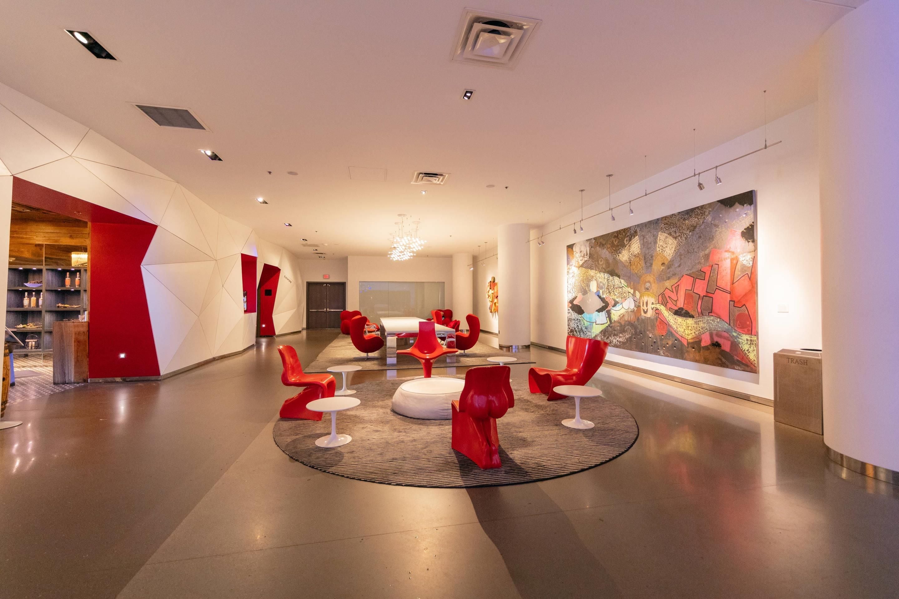 A modern lobby with a central seating area, a large abstract painting, and a visible trash bin.
