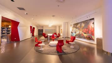A modern lobby with a central seating area, a large abstract painting, and a visible trash bin.