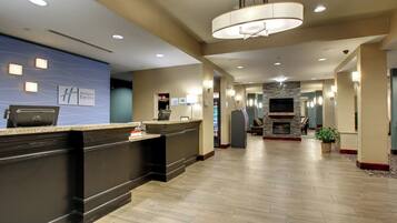A hotel reception area with a reception desk, a flat-screen TV, and a fireplace.