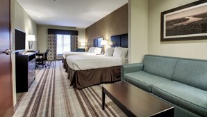A hotel room with a large bed, a sofa, a desk with a lamp, and a framed picture on the wall. - Holiday Inn Express Hotel & Suites Natchez South by IHG (Natchez)