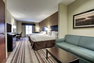 A hotel room with a large bed, a sofa, a desk with a lamp, and a framed picture on the wall.