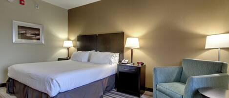A hotel room with a large bed, two bedside tables with lamps, a chair, and a small table.