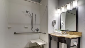 A bathroom with a shower, grab bar, sink, and mirror. - Holiday Inn Express Hotel & Suites Natchez South by IHG (Natchez)