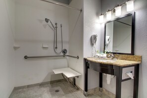A bathroom with a shower, grab bar, sink, and mirror. - Holiday Inn Express Hotel & Suites Natchez South by IHG (Natchez)