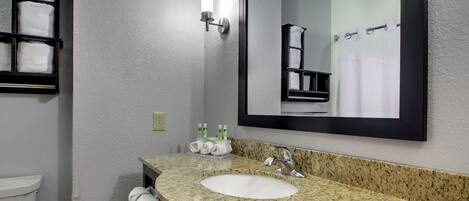 A bathroom with a granite countertop sink, a mirror, and a towel rack.
