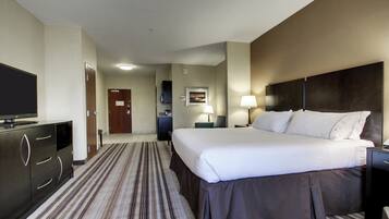Una habitación de hotel con cama, televisor, escritorio, lámpara y puerta.
