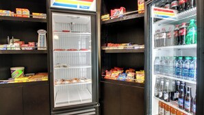 Máquina expendedora con diversas opciones de bocadillos y bebidas, como papas fritas, refrescos y agua embotellada.
