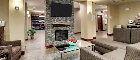 Un hall de hotel con chimenea, zona de estar y mostrador de recepción.