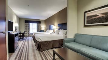 A hotel room with a large bed, a sofa, a desk with a lamp, and a framed picture on the wall.