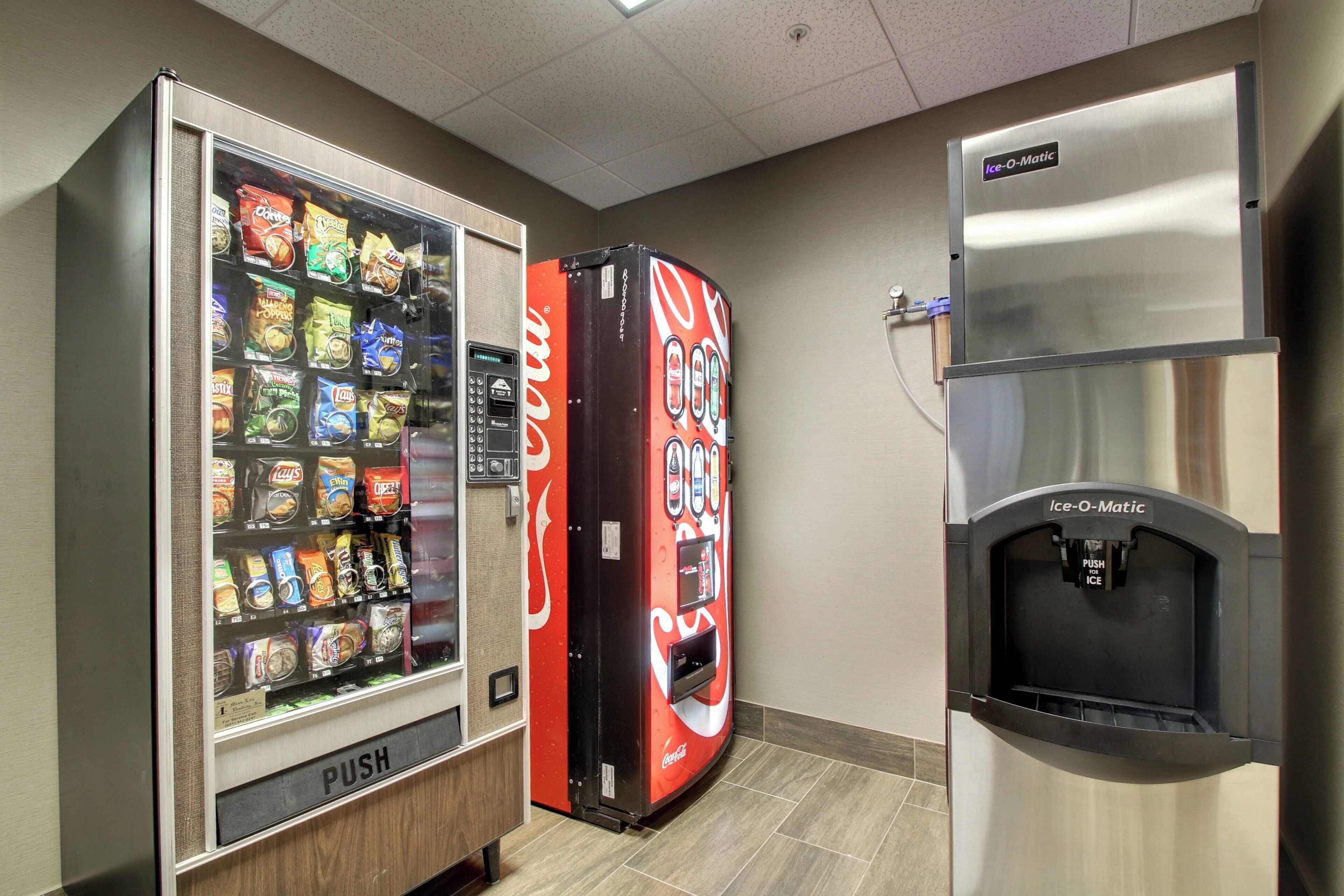 Zona de máquinas expendedoras con una máquina de Coca-Cola y un dispensador de hielo.