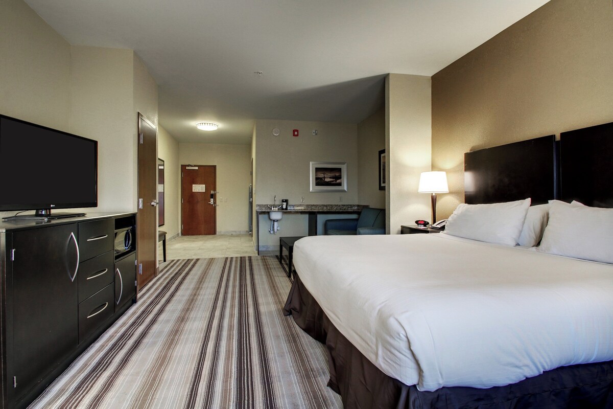 A hotel room with a bed, a TV, a desk with a chair, and a bathroom.