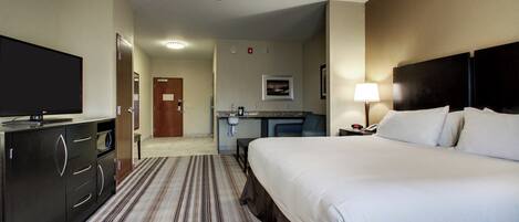 A hotel room with a bed, a TV, a desk with a chair, and a bathroom.