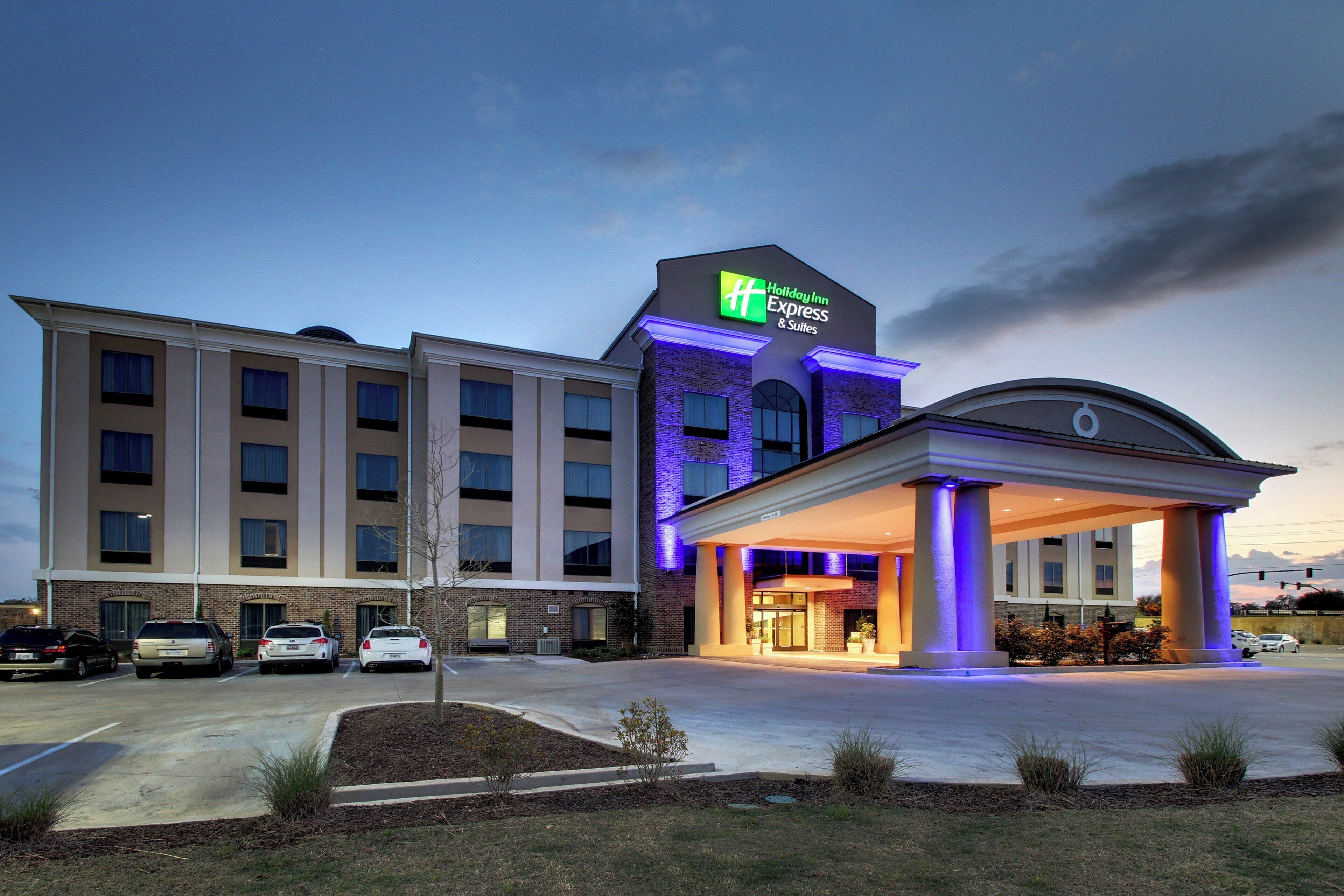 A Holiday Inn Express & Suites hotel with a brick facade, a covered entrance, and a parking lot.