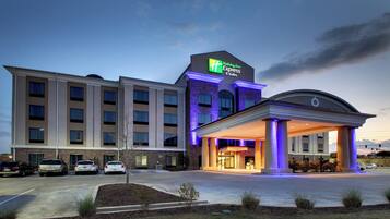A Holiday Inn Express & Suites hotel with a brick facade, a covered entrance, and a parking lot.