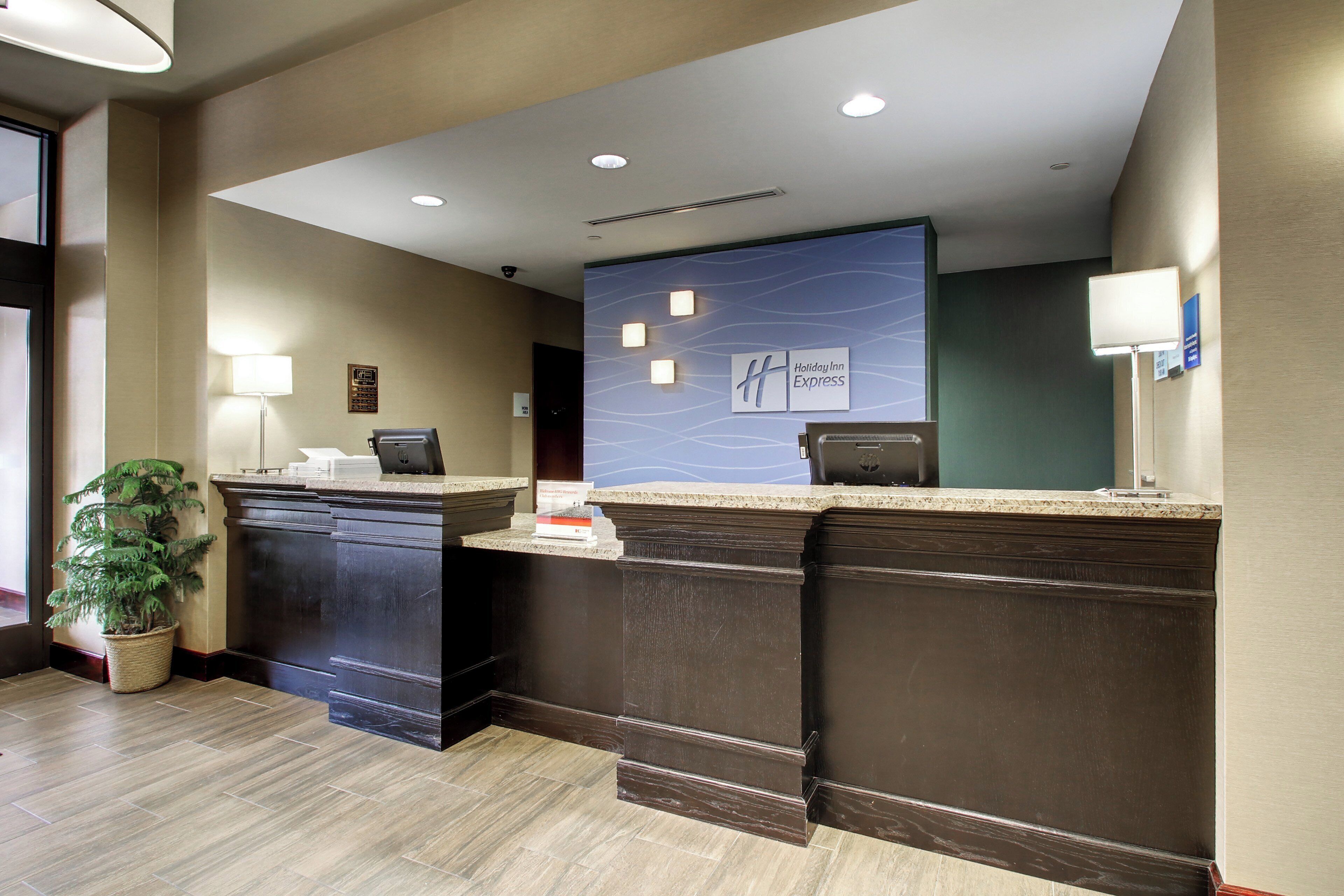 A reception desk with a marble top, a potted plant, and a wall-mounted sign for Holiday Inn Express.
